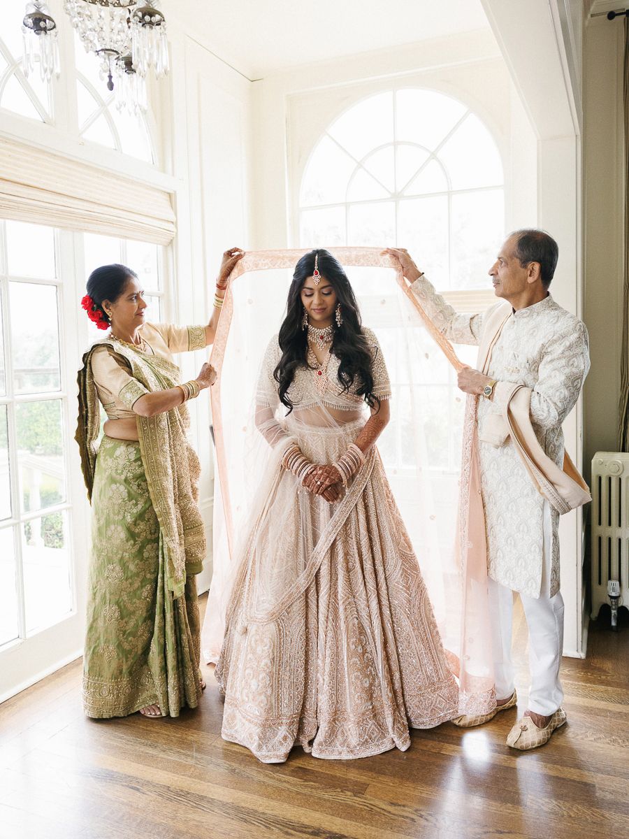 Two people in traditional South Asian attire dance together in a bright indoor space with hardwood floors.