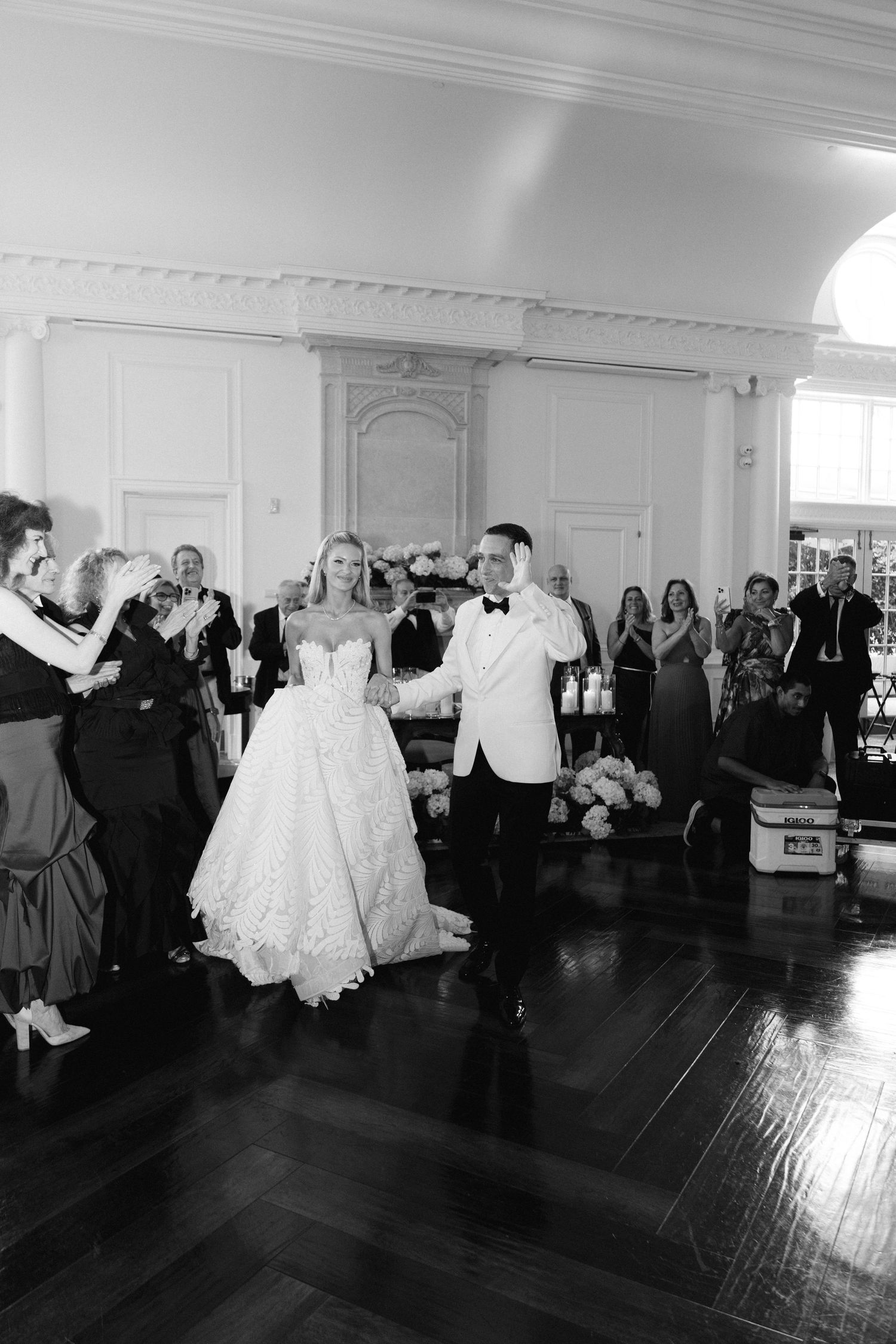 A couple shares their first dance at an elegant wedding reception while guests watch from the sides of the ballroom.