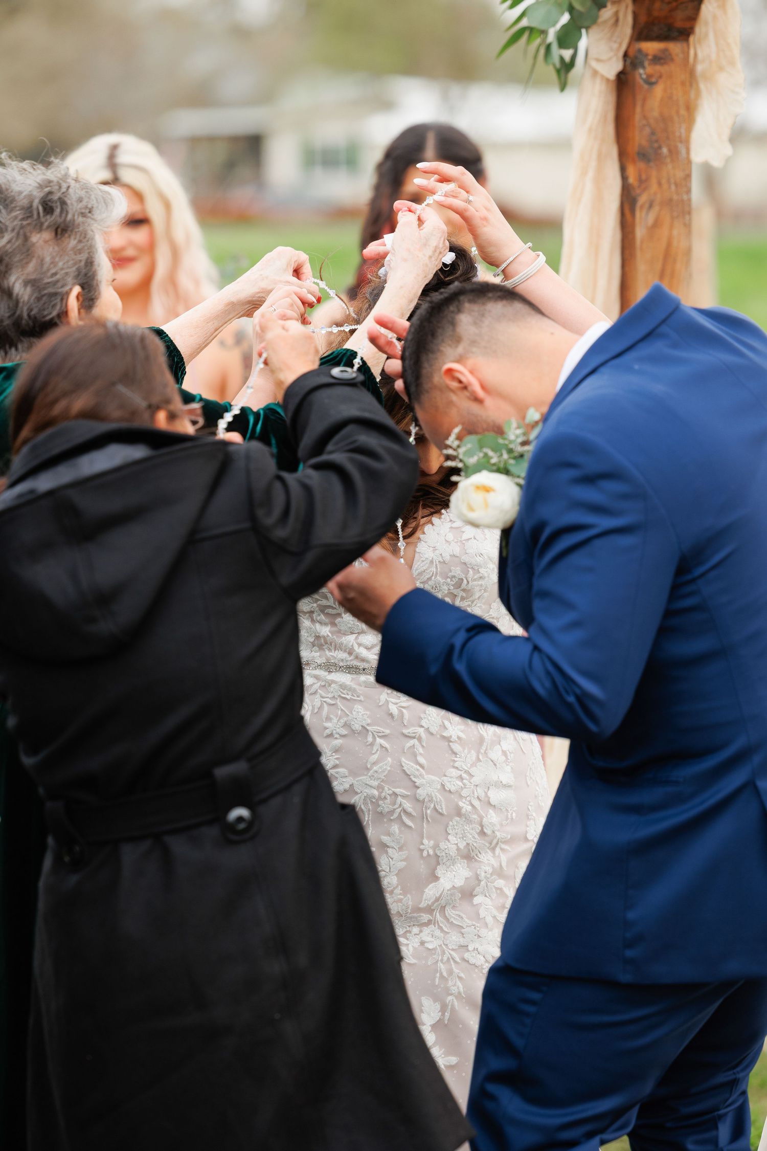 A joyful moment at an outdoor wedding ceremony as guests share champagne under a rustic wooden pergola.