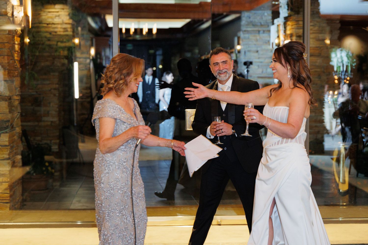 Couple dancing together during a wedding celebration in a rustic brick-walled venue with warm lighting.