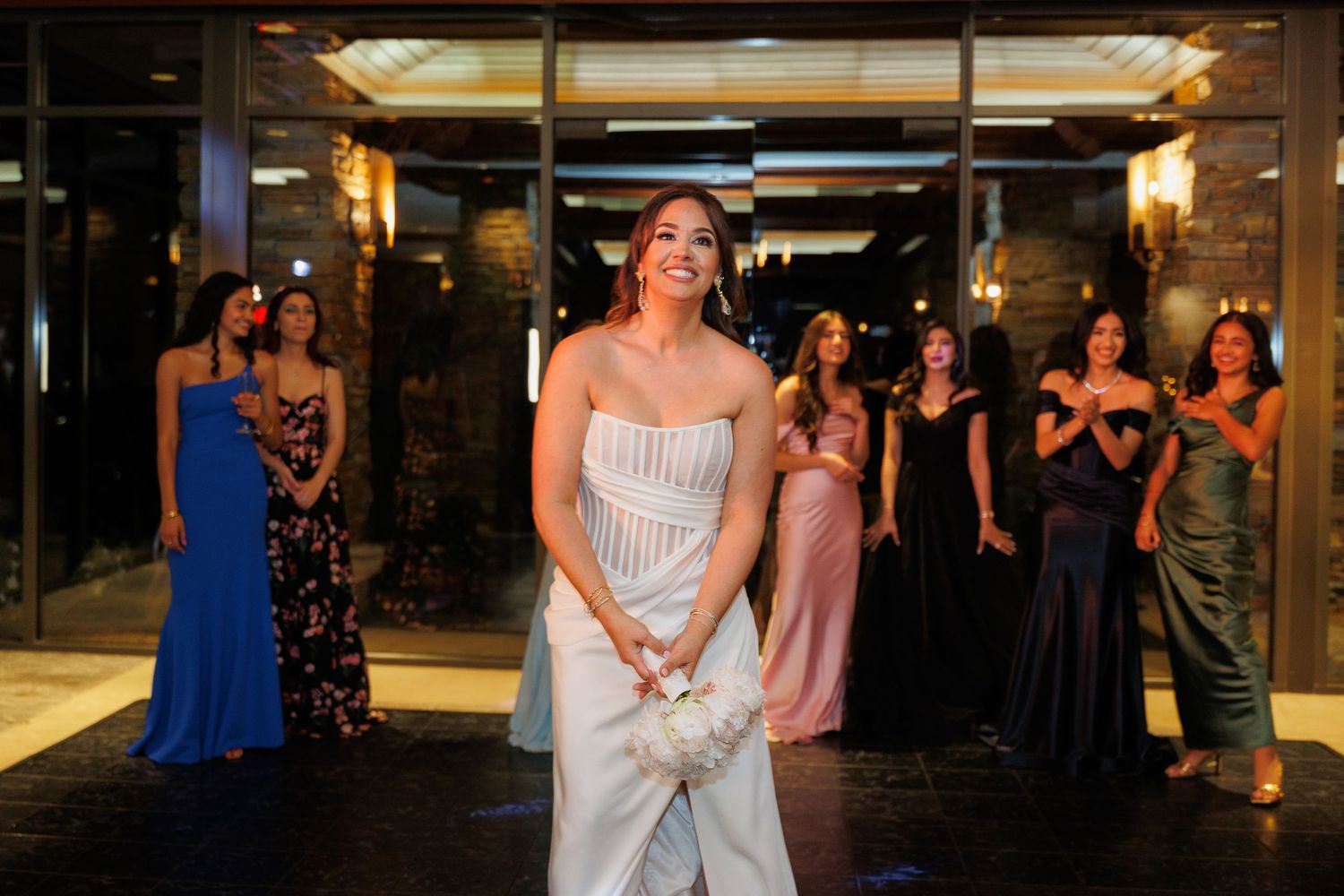 Wedding guests dance and celebrate on a dimly lit dance floor at an evening reception.