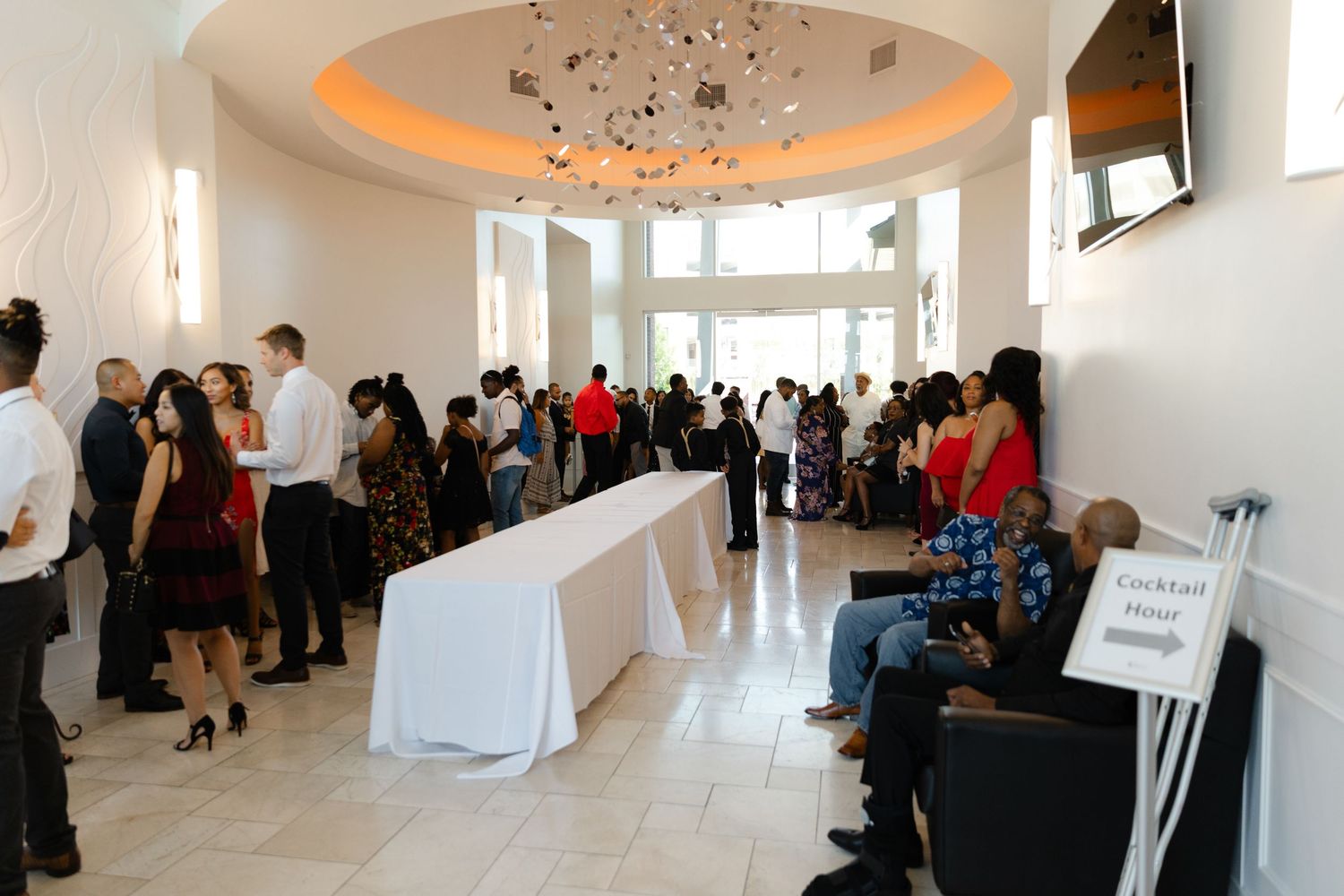 People gathered in a modern white interior space with circular ceiling details during what appears to be an event or function.