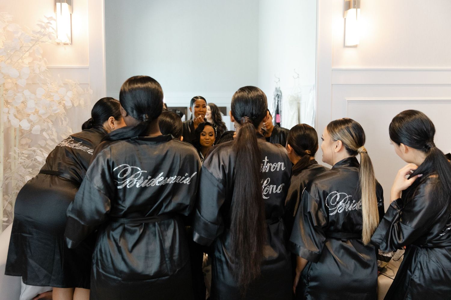 A group wearing matching black satin robes huddle together in a circle before a special event.