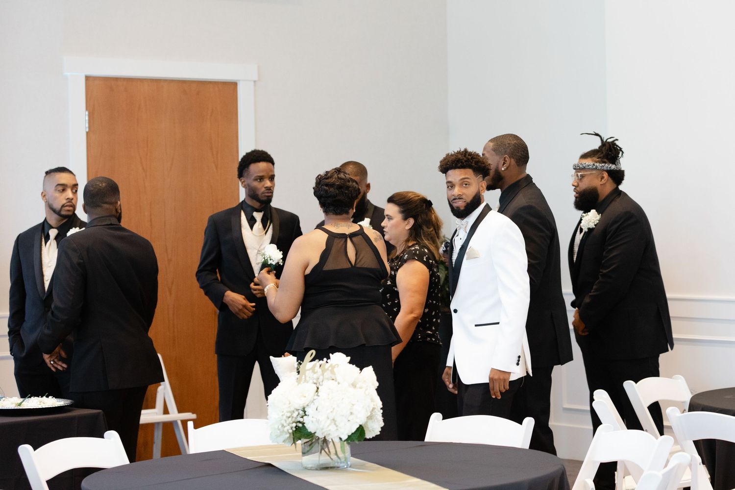 A panoramic view of a formal event with people in black and white attire gathered in a bright indoor space.