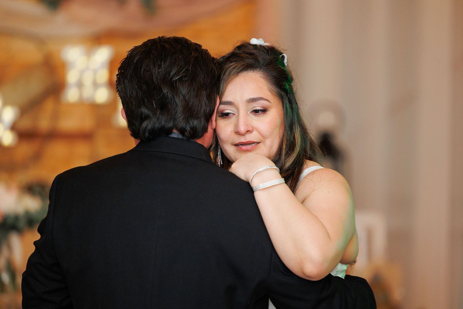 A couple shares a romantic dance together at an elegant wedding reception with warm lighting and decor.