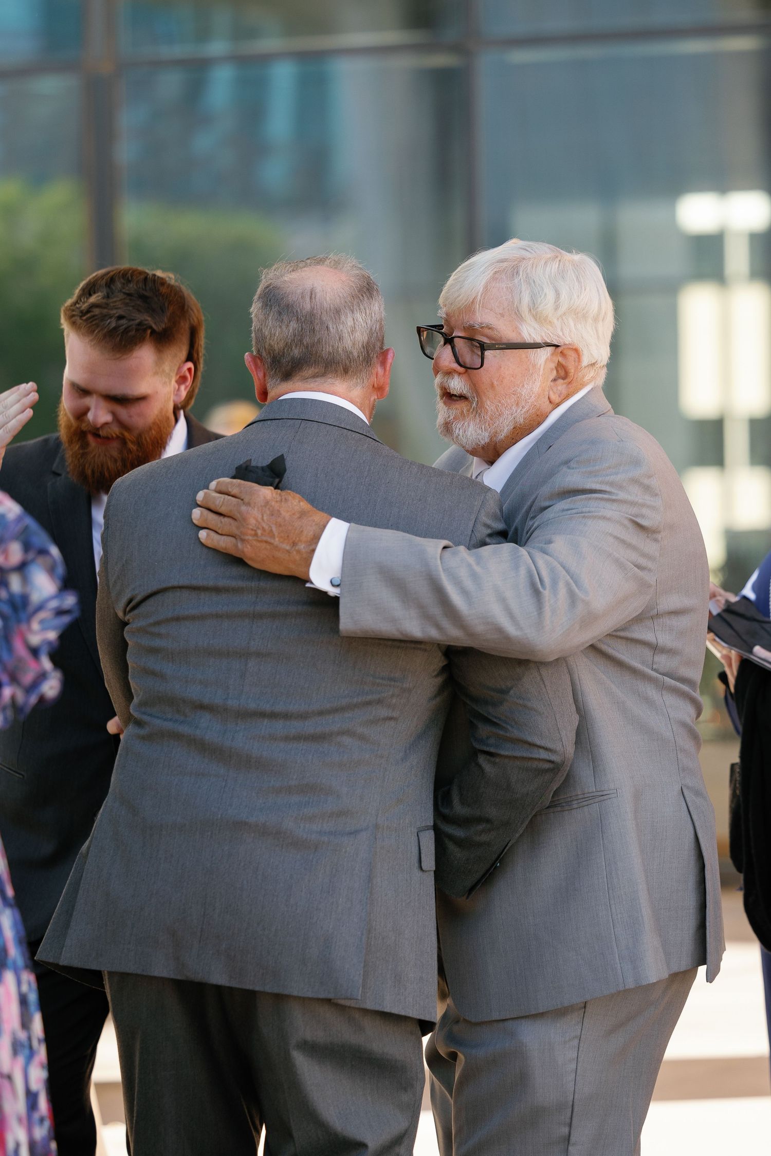 A sequence of photos showing two people in suits embracing and sharing an emotional moment.