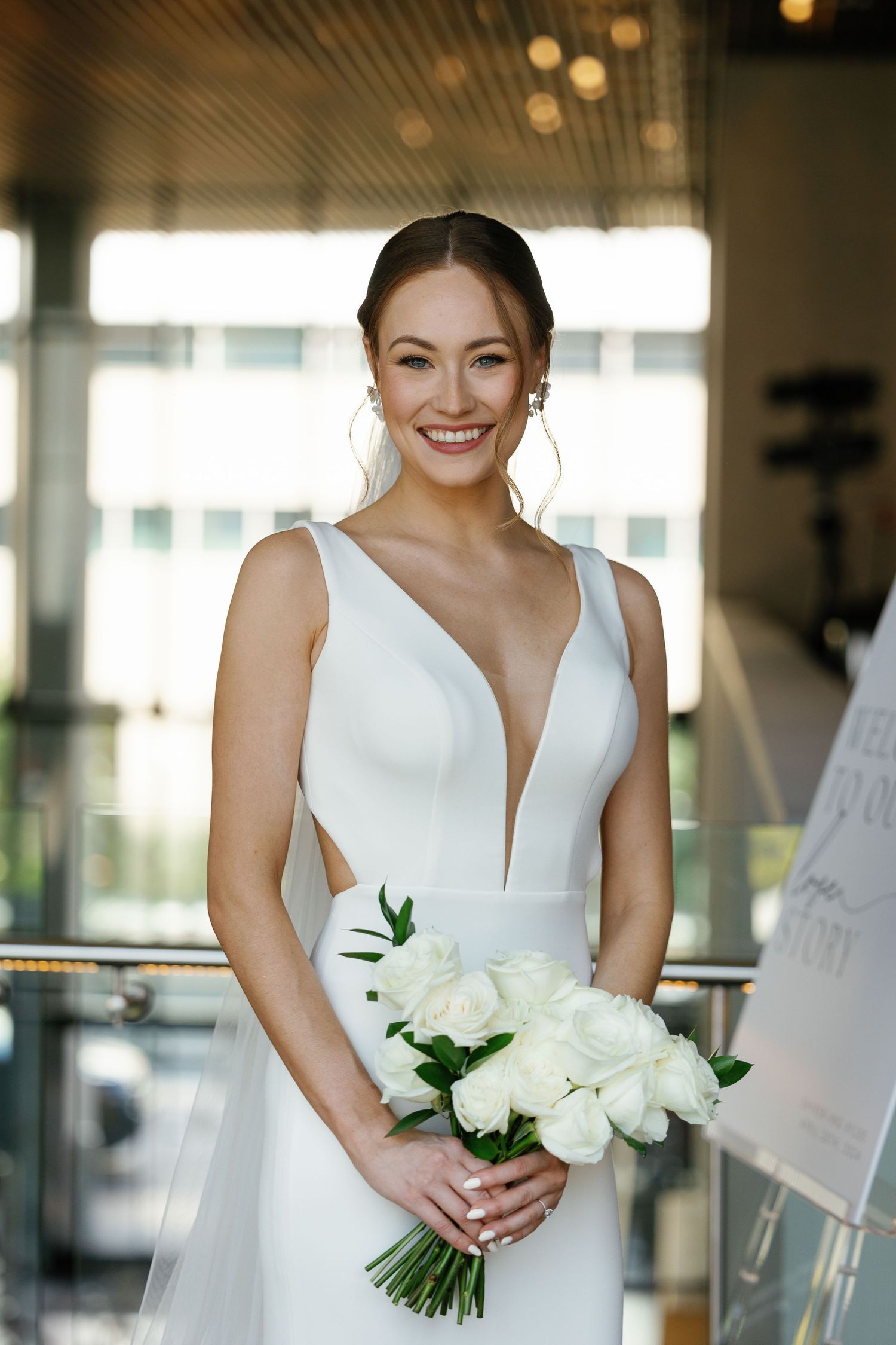 A bride in a white wedding dress holds a classic white floral bouquet during her wedding day preparations.