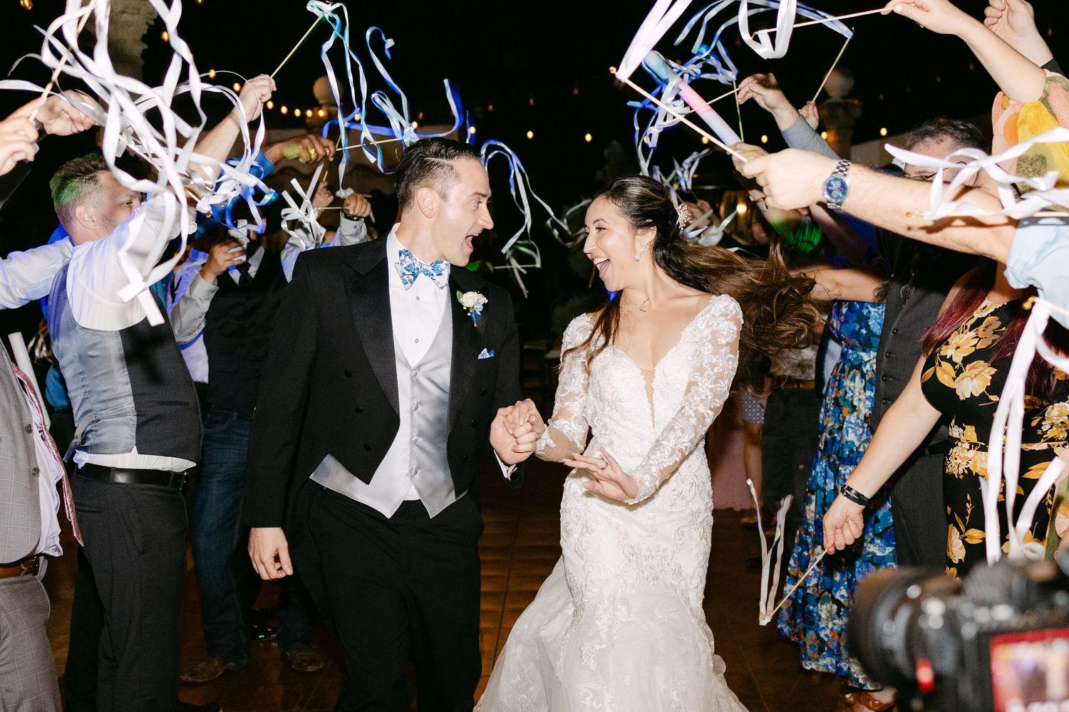 Newlyweds dance at their wedding reception while guests wave sparklers creating a magical nighttime atmosphere.