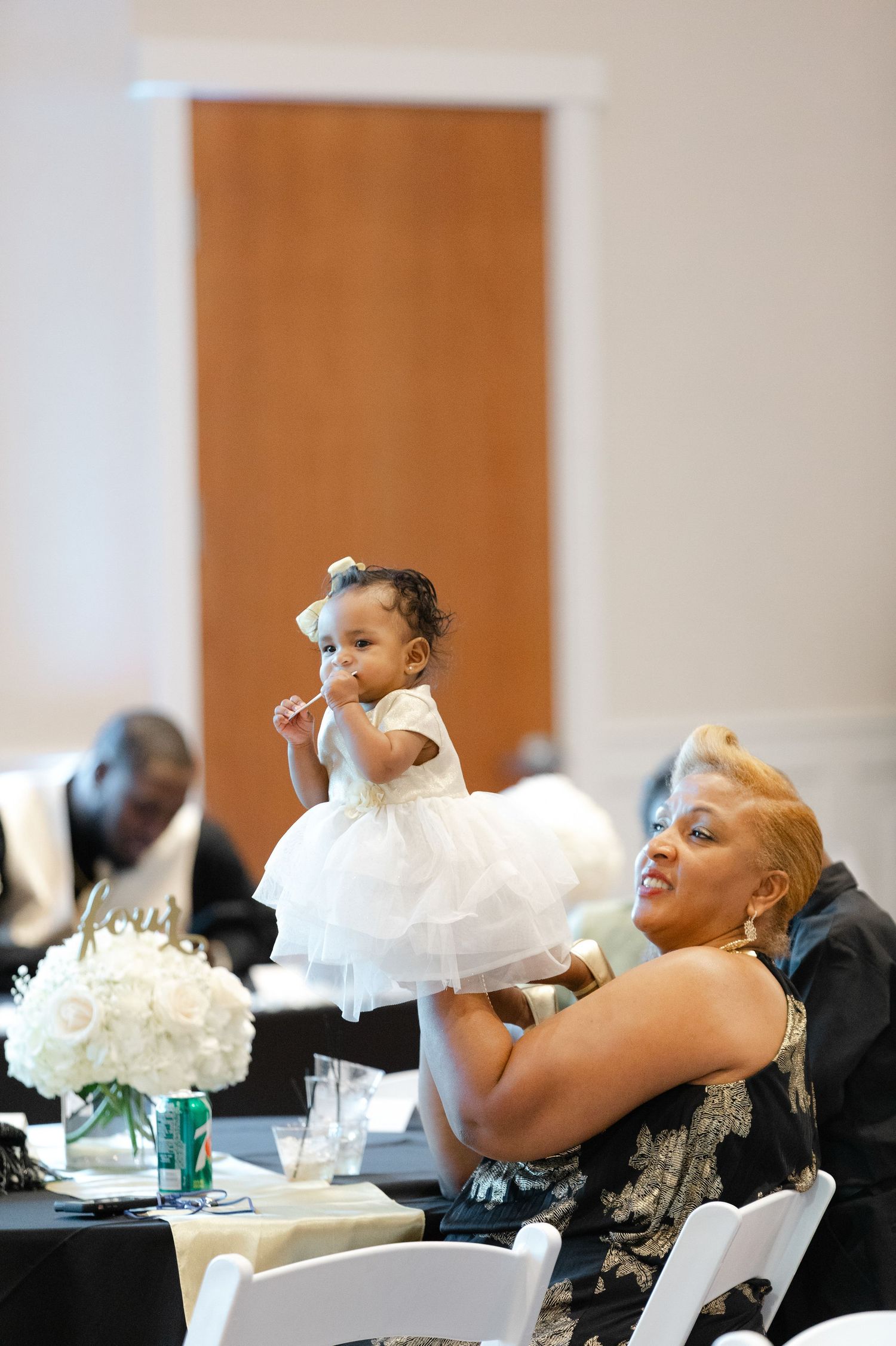 Wedding guests laugh and celebrate together at a reception table with white tablecloths and decorations.