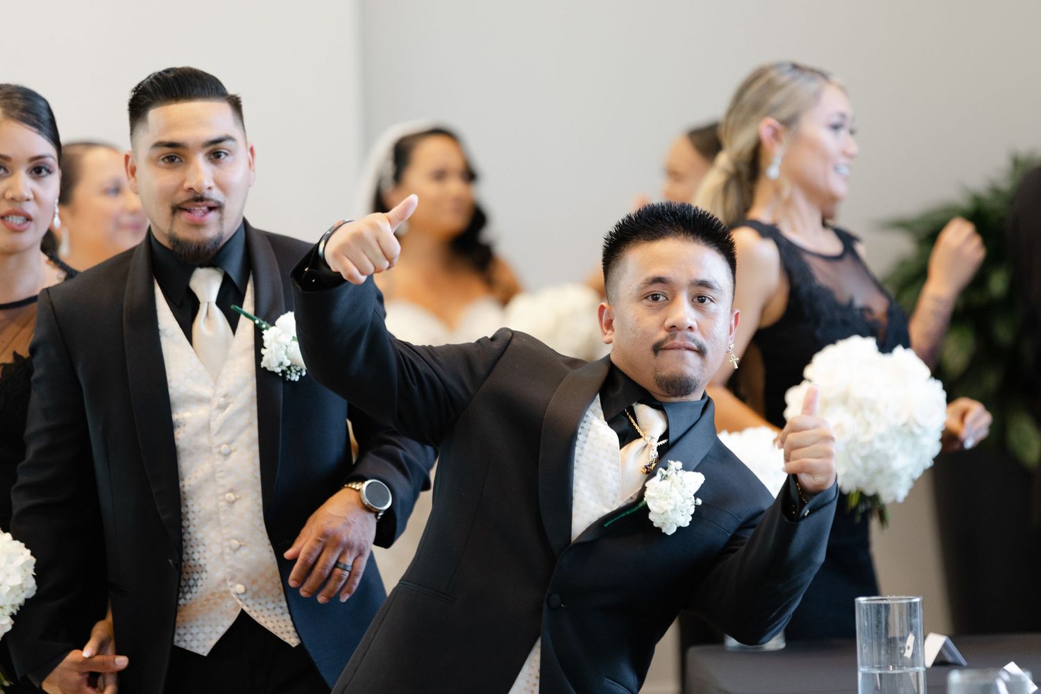 Wedding party members in formal attire pose and smile during an elegant indoor celebration.