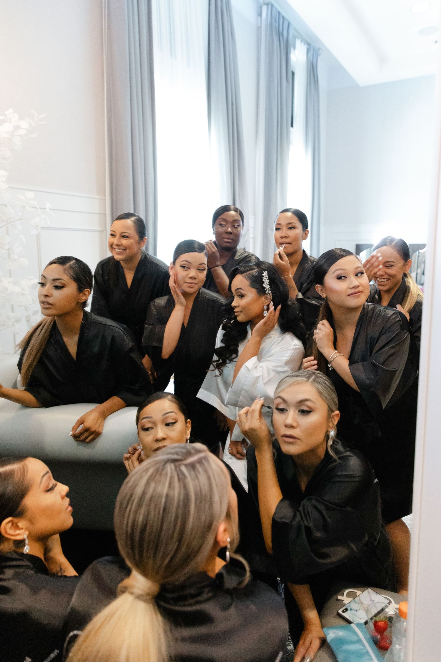 Models in black outfits gather backstage during fashion show preparations.