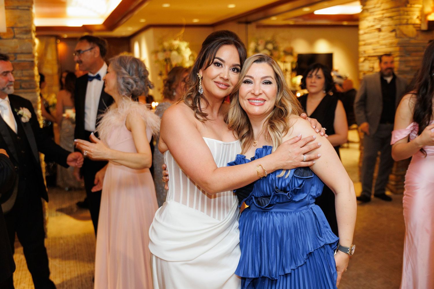Wedding guests dancing and celebrating together on the dance floor at an elegant indoor reception venue.