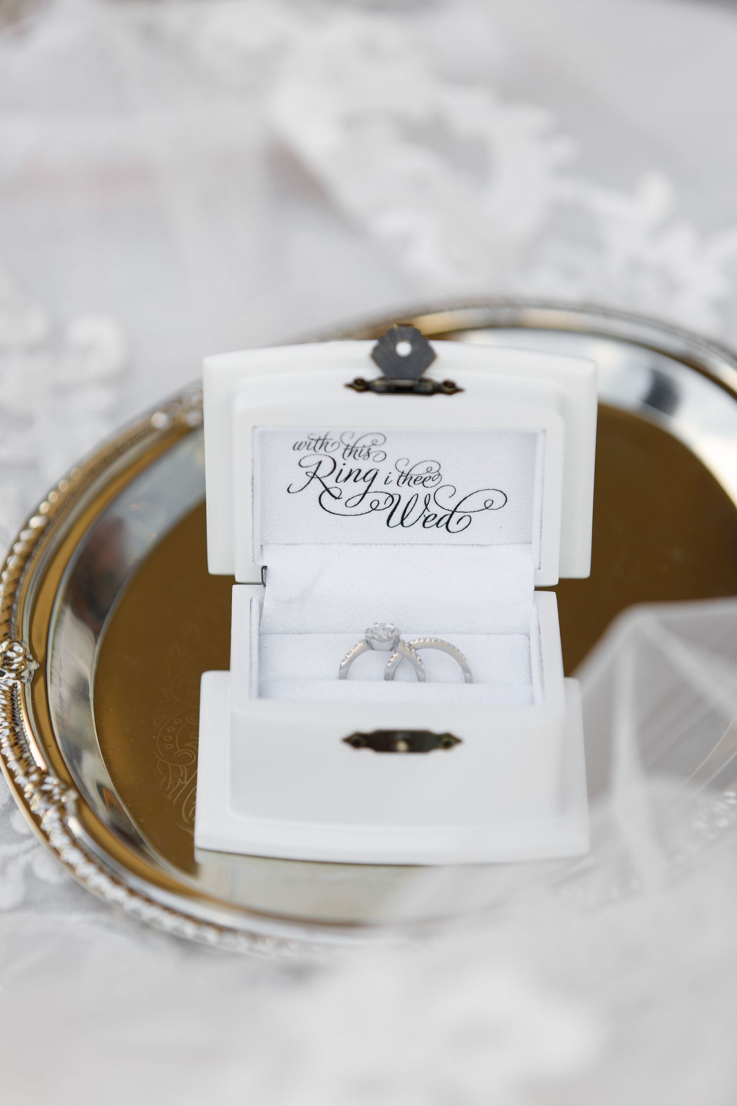 A series of elegant wedding ring detail shots displayed on white paper against a soft, blurred background.