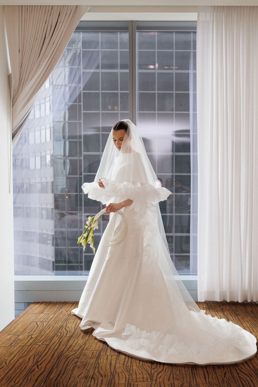 A wedding dress photoshoot sequence showing flowing white gown against floor-to-ceiling windows in a bright room.