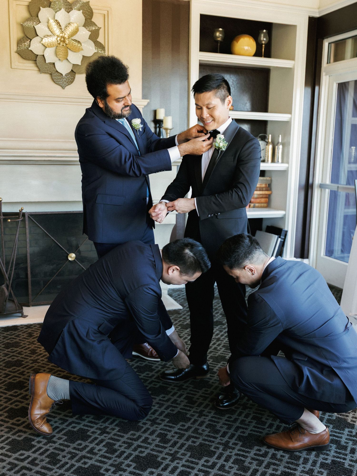 A series of playful moments showing groomsmen in navy suits wrestling and laughing on a patterned carpet.