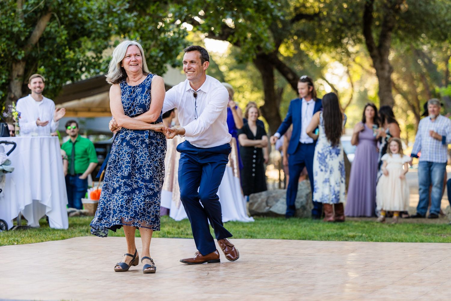 Couples dancing together outdoors at a summer evening social gathering in a park setting.