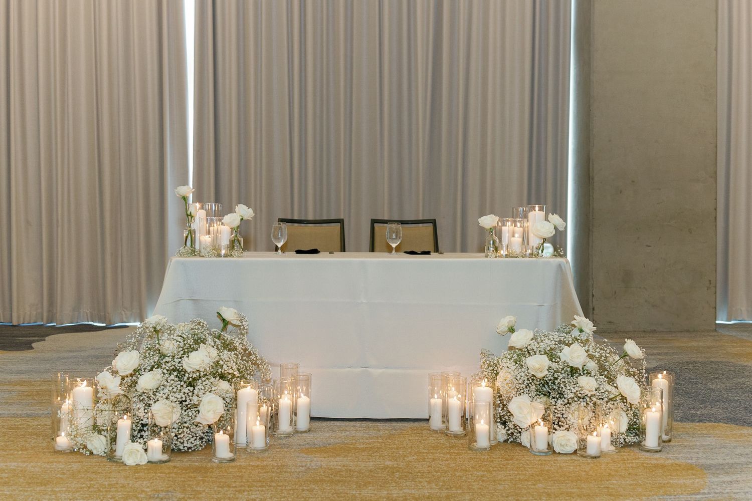 Elegant wedding reception venue with white drapes, floral arrangements, and glowing candles creating a romantic atmosphere.