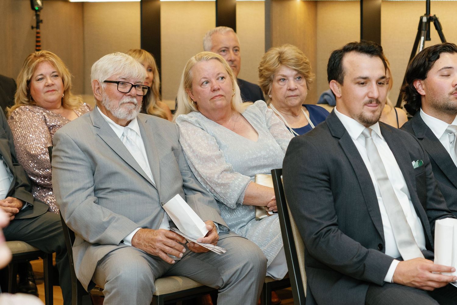 Business professionals seated in rows at a conference or meeting venue listen attentively to a presentation.