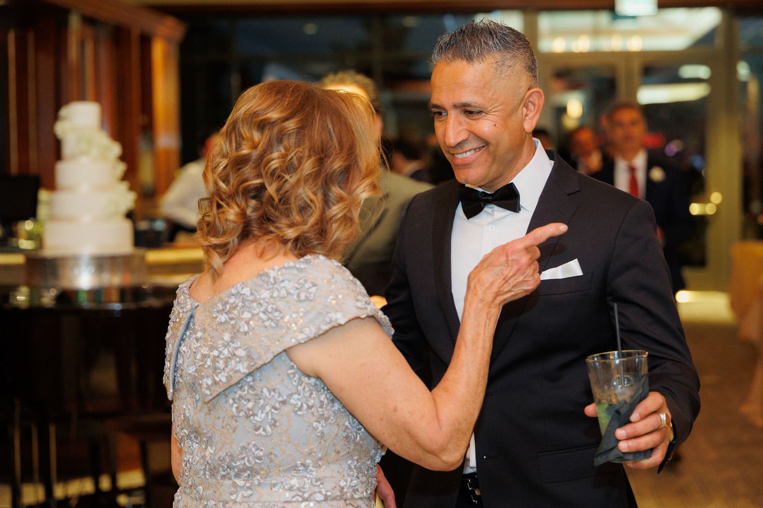 A couple shares a joyful dance together at a wedding reception in formal attire.