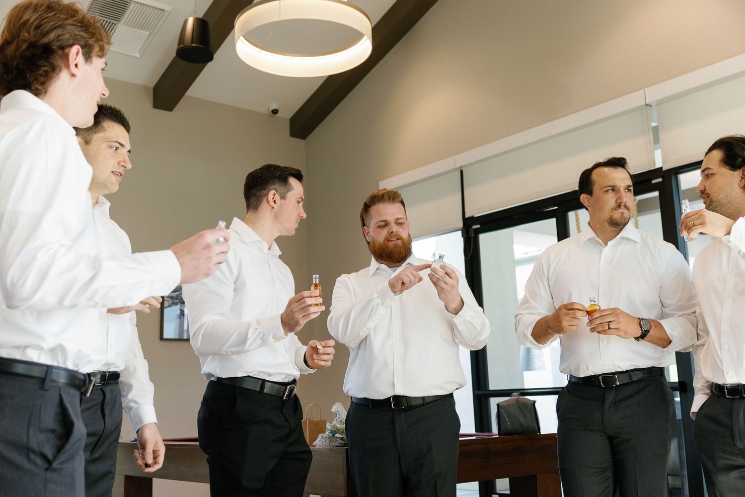 A group in formal business attire gathers in an office space for a casual conversation and interaction.