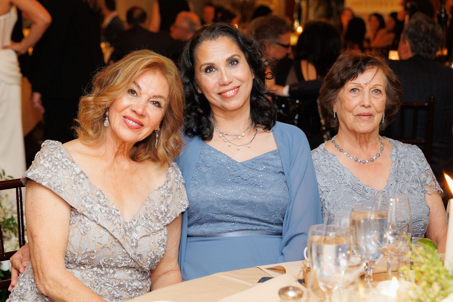 A group of elegantly dressed guests enjoying a formal dinner event at a banquet table.