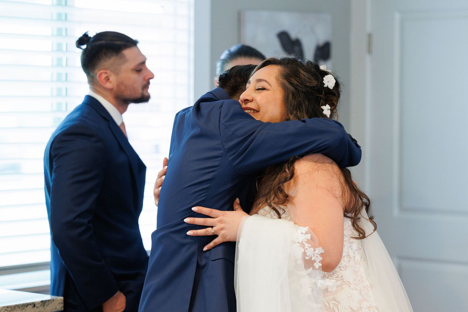 A bride and groom share an intimate first look moment in a bright white room before their wedding ceremony.