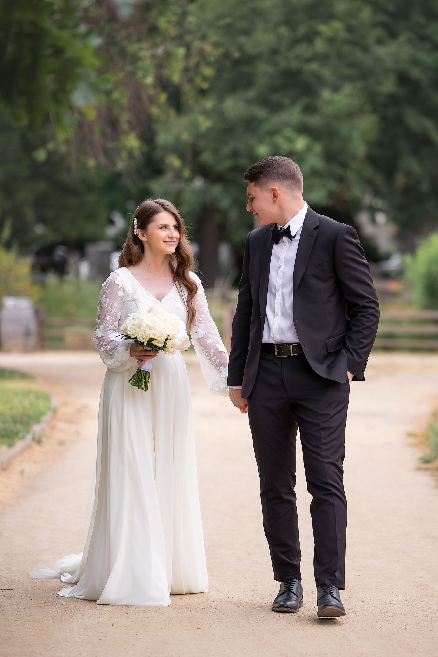 Romantic wedding photo series showing couple posing on tree-lined path.