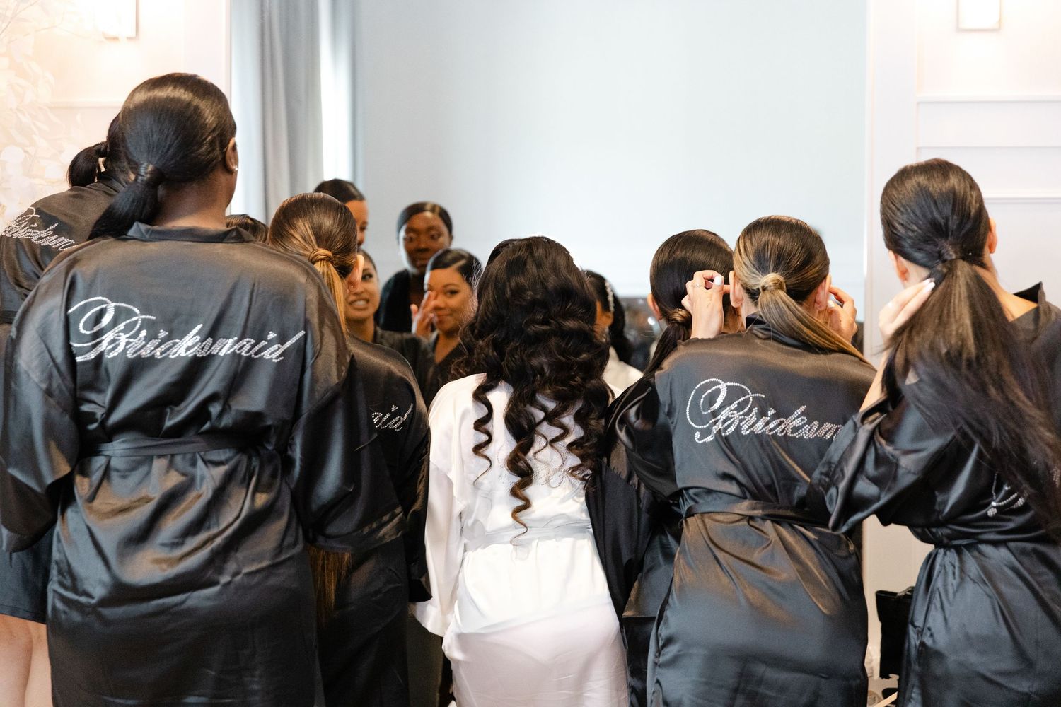 Group of people wearing matching black jackets gather together in an indoor setting.