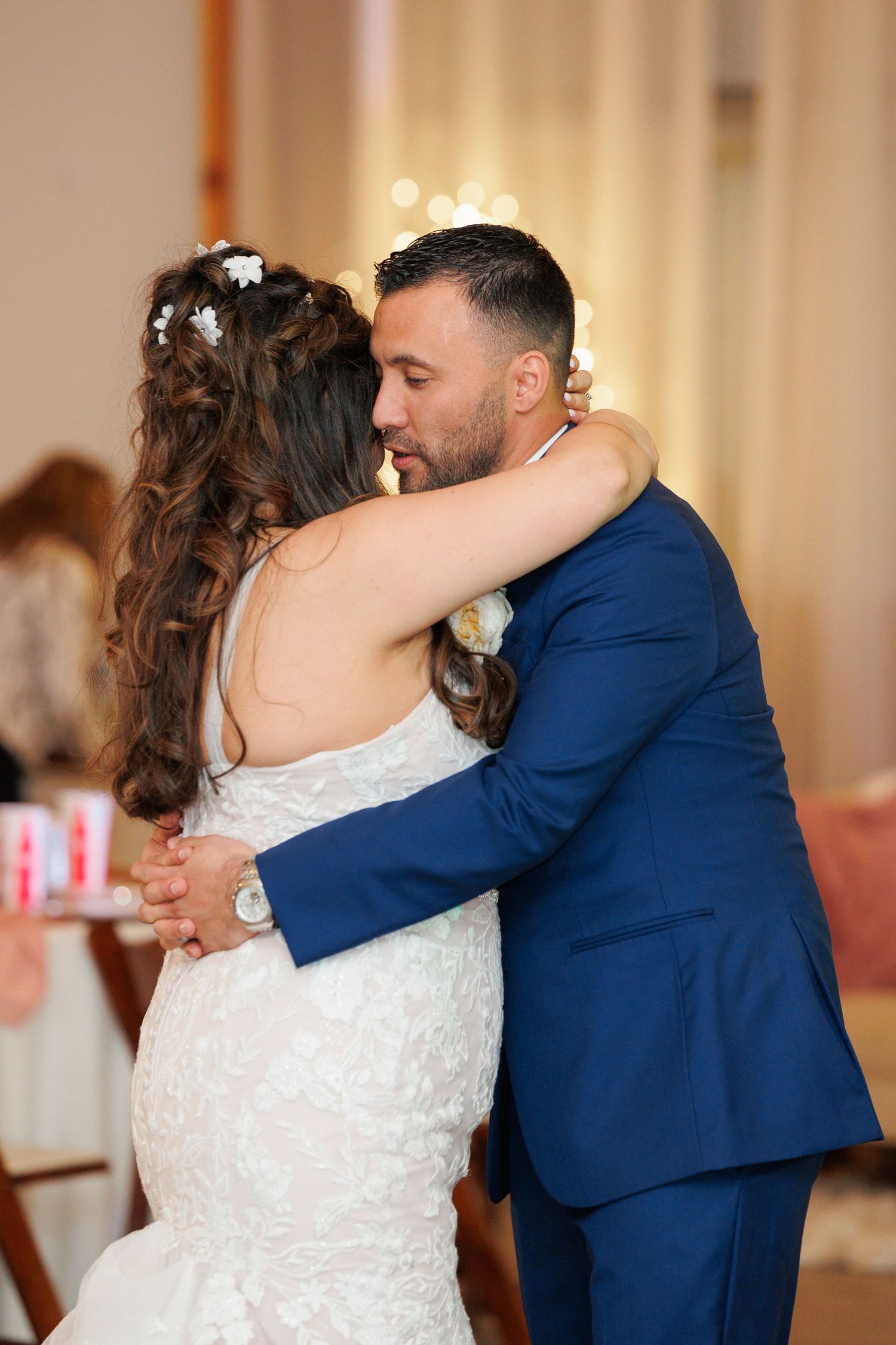 A couple shares an intimate first dance moment at their wedding reception in a warmly lit ballroom.