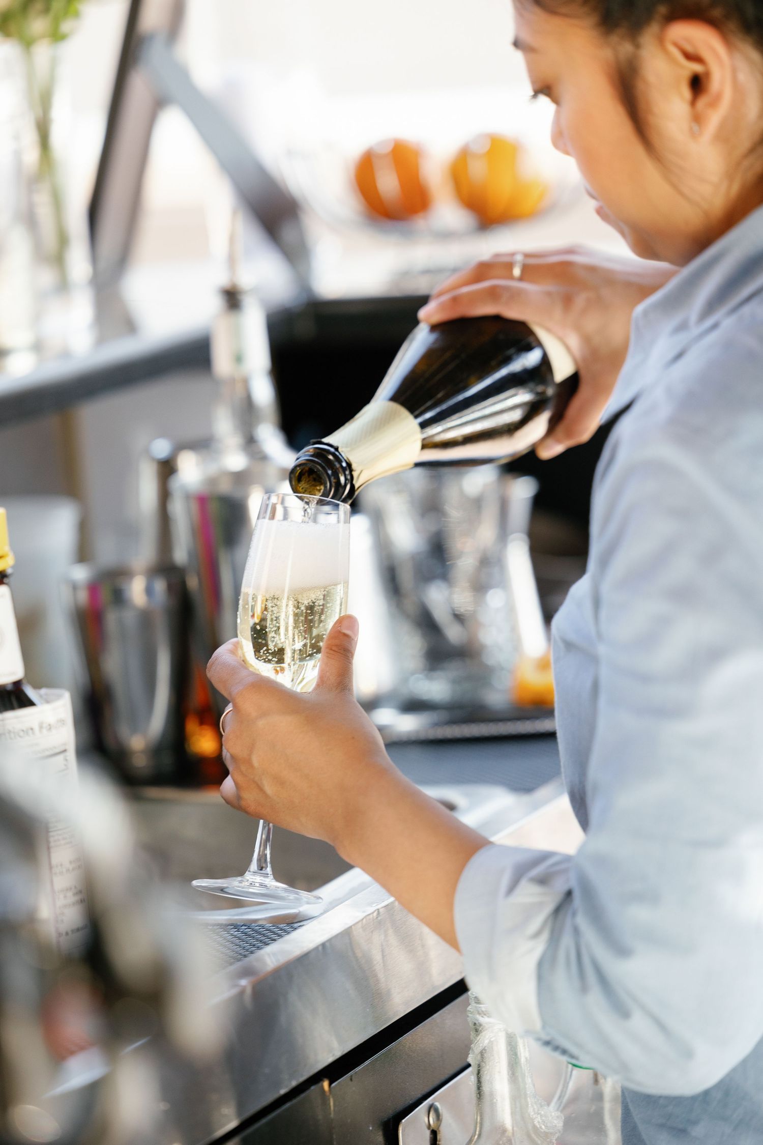 Bartender pours sparkling wine into elegant champagne glasses at an upscale bar counter.