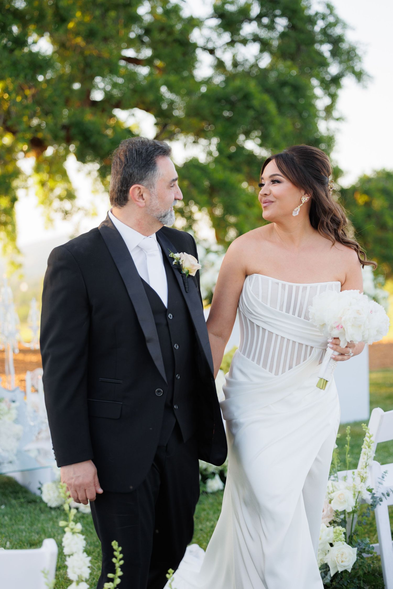 A couple shares joyful moments together outdoors during their wedding celebration in a garden setting.