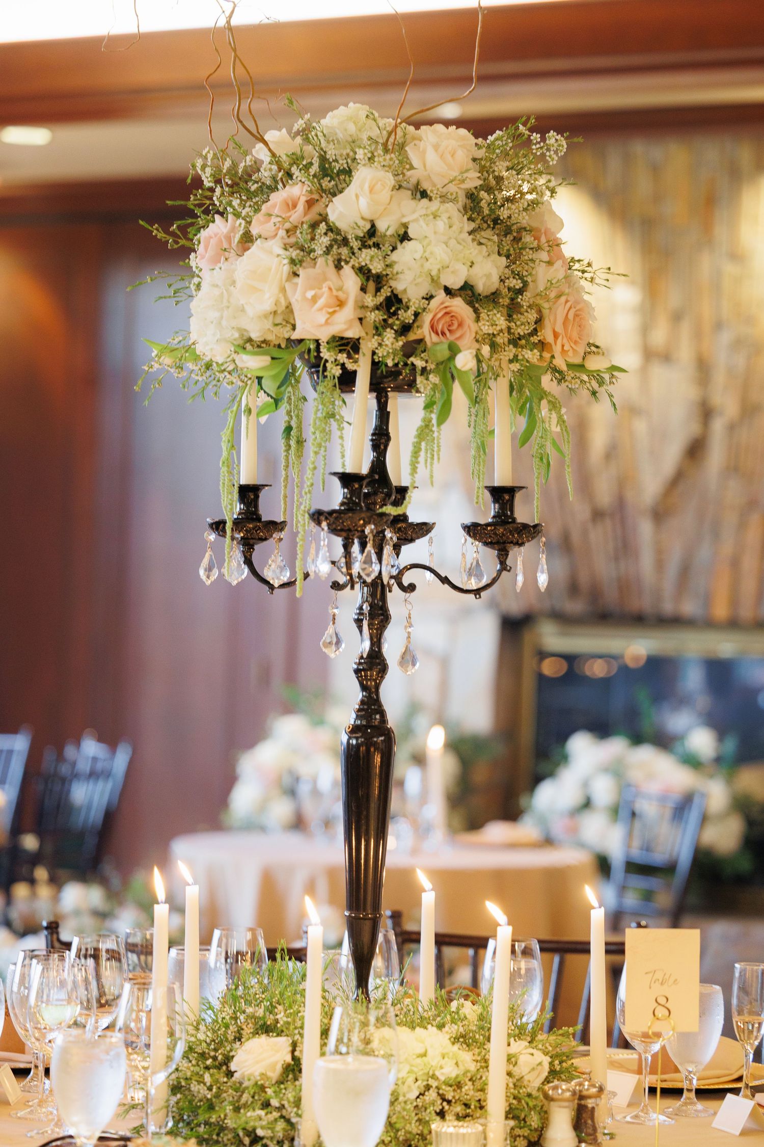 Elegant wedding centerpiece featuring black candelabra with crystal drops topped with pink and white floral arrangement.