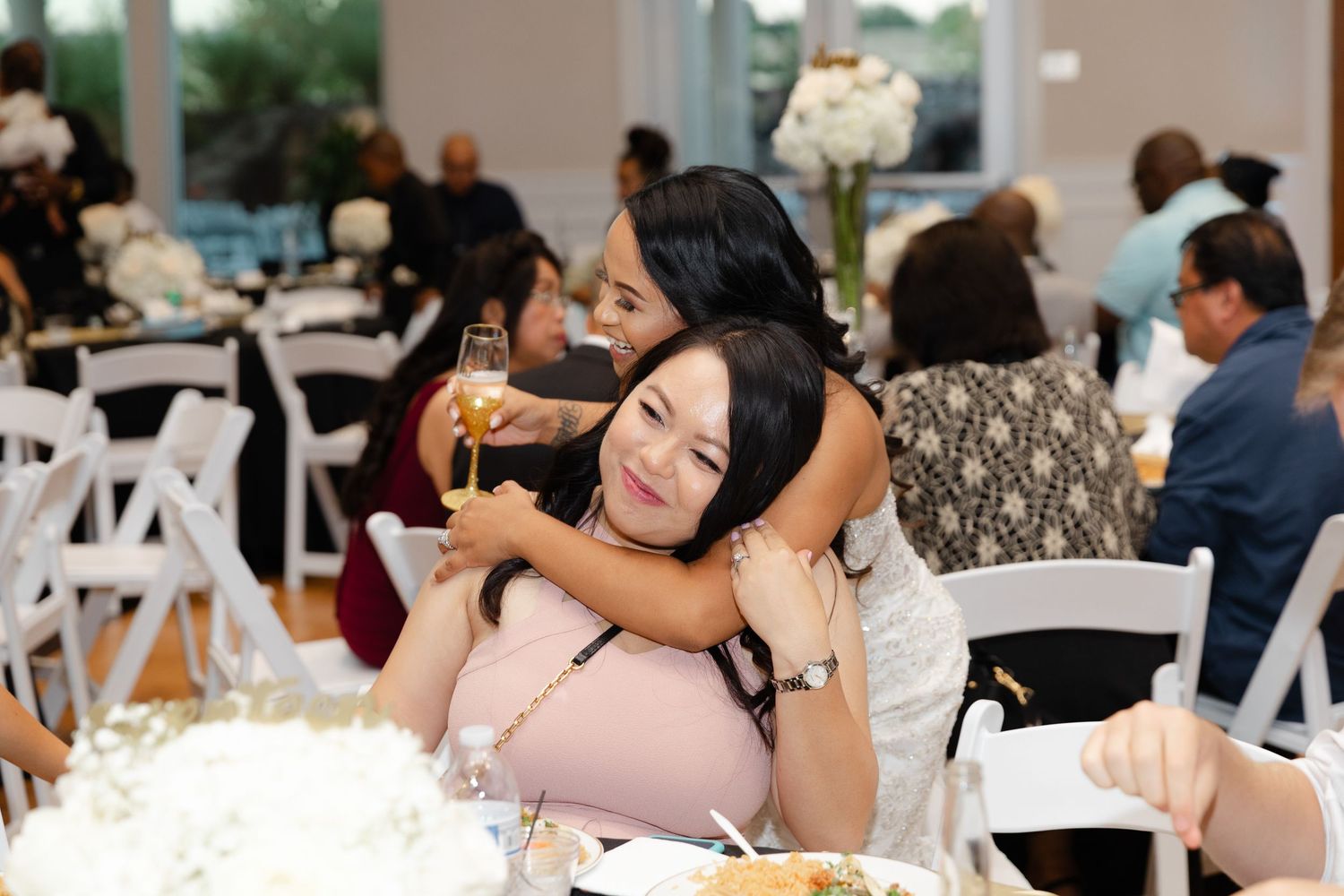 Wedding guests enjoy a reception dinner at tables decorated with white linens and centerpieces.