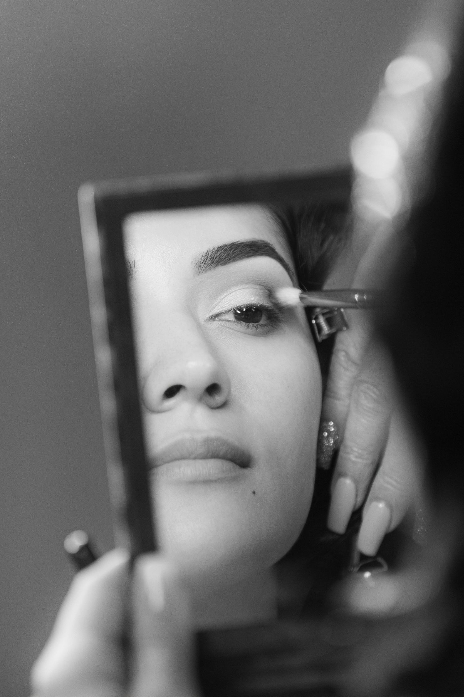 A black and white close-up photo shows partial facial features through a blurred or fragmented composition.