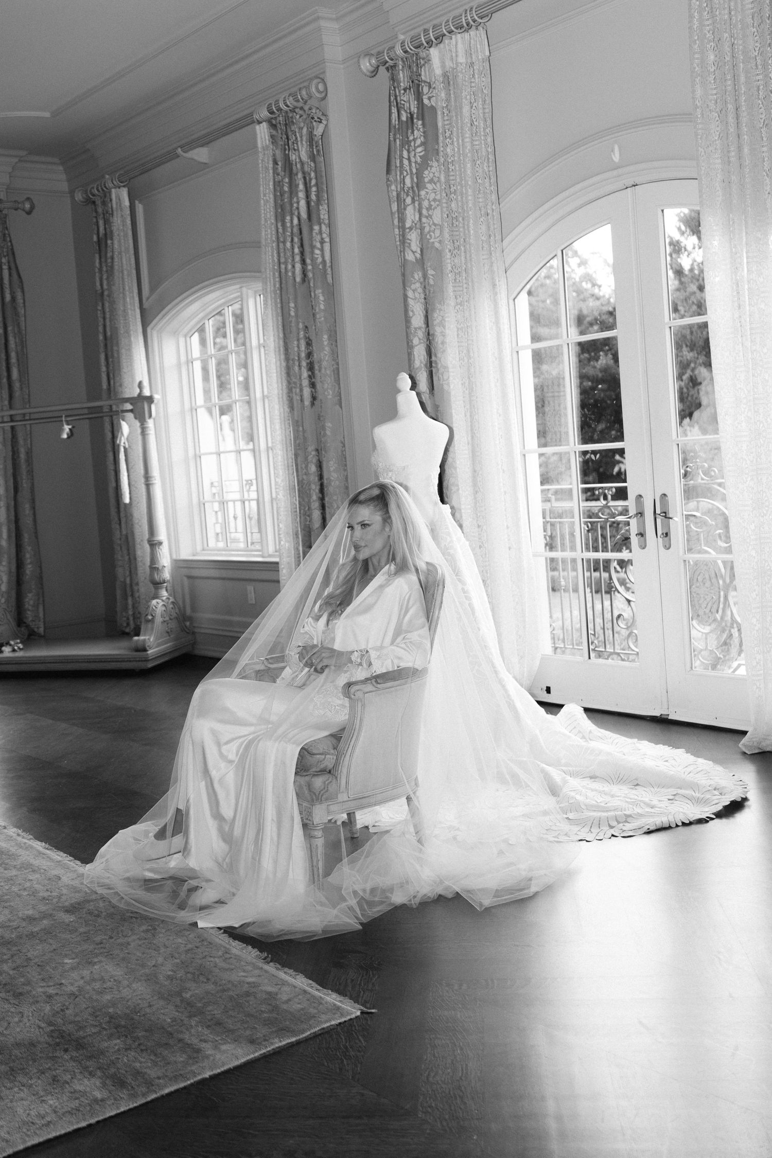 A series of black and white photos showing a bride in a flowing white dress posing gracefully in an elegant room with windows.