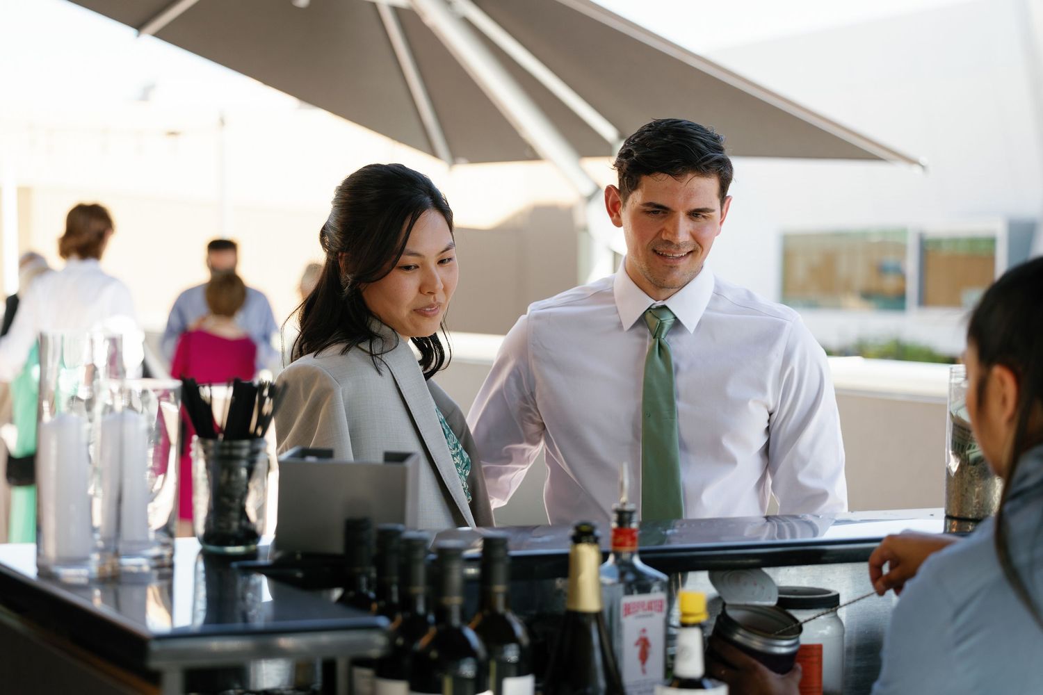 Professional bartenders mix cocktails behind a modern bar counter during a busy evening service period.