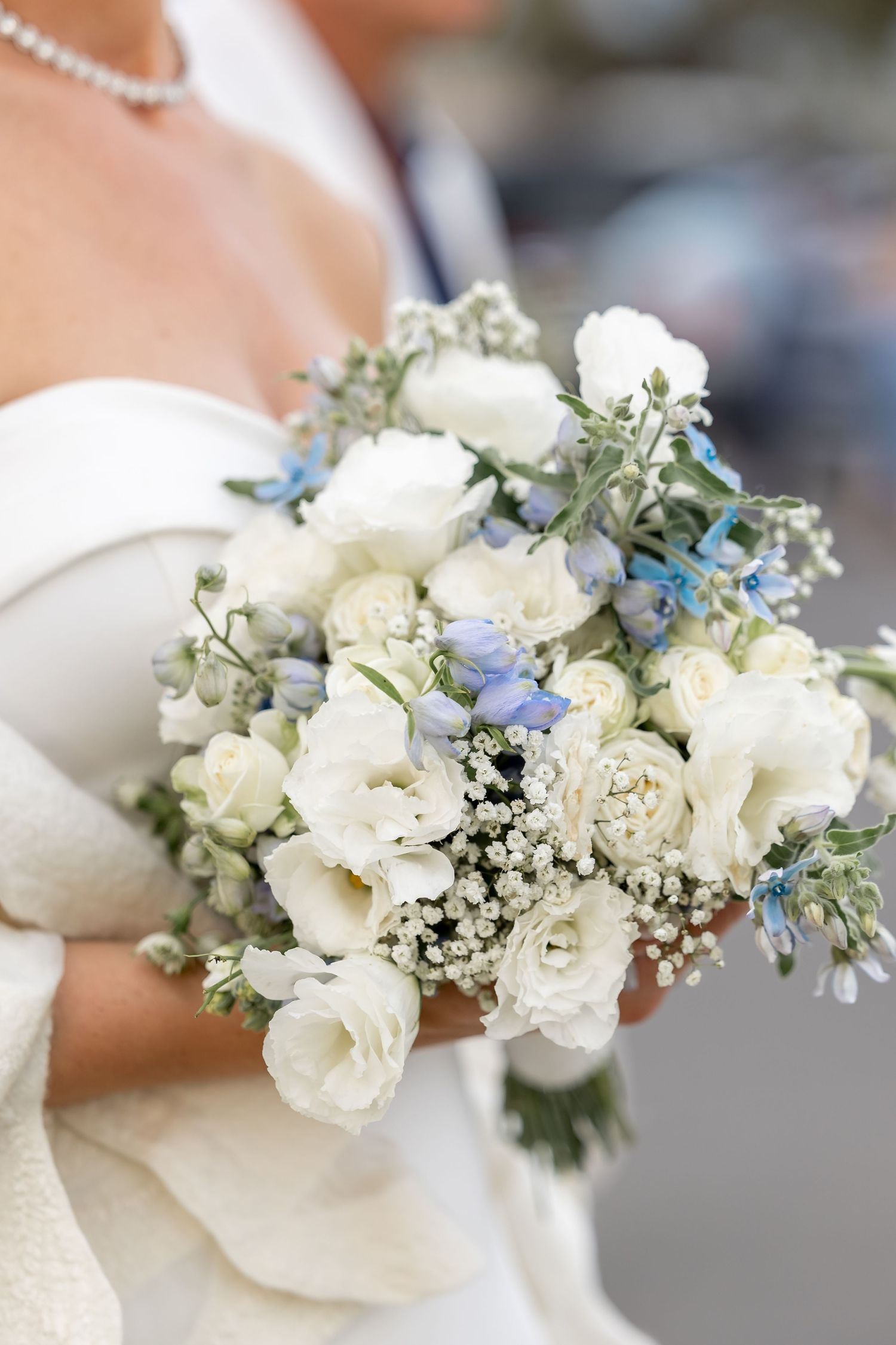 Delicate white and blue floral crown with roses and baby's breath against a light background.