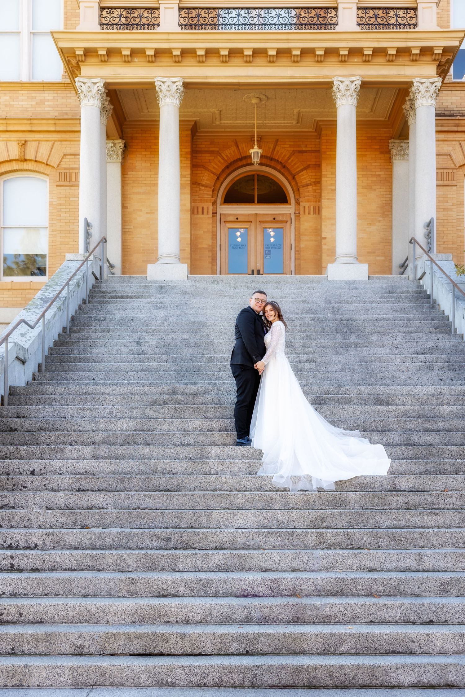 Wedding couple photographed in sequence on grand stone steps of historic building.