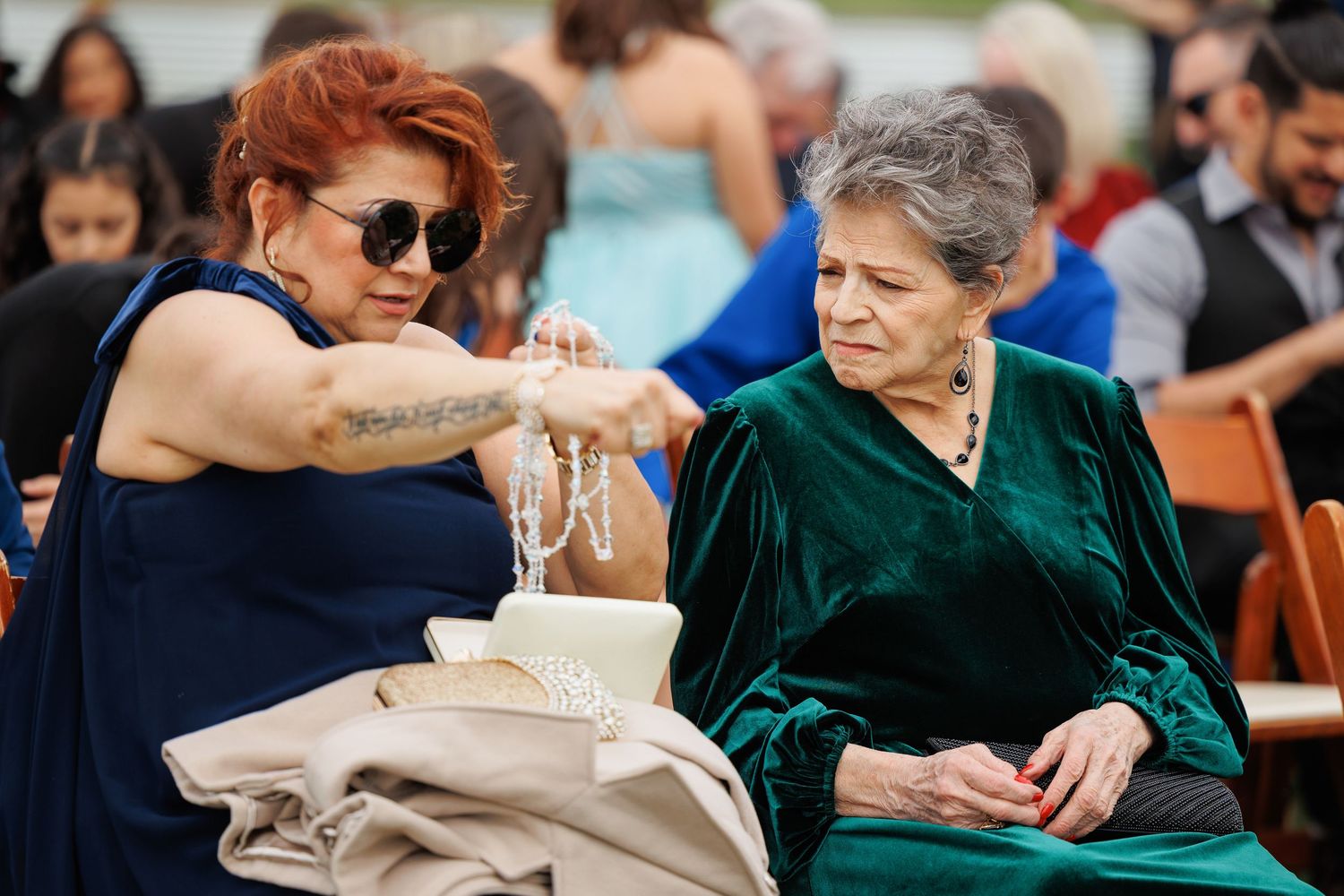 A diverse group of people sit together at outdoor tables during a casual gathering or event.