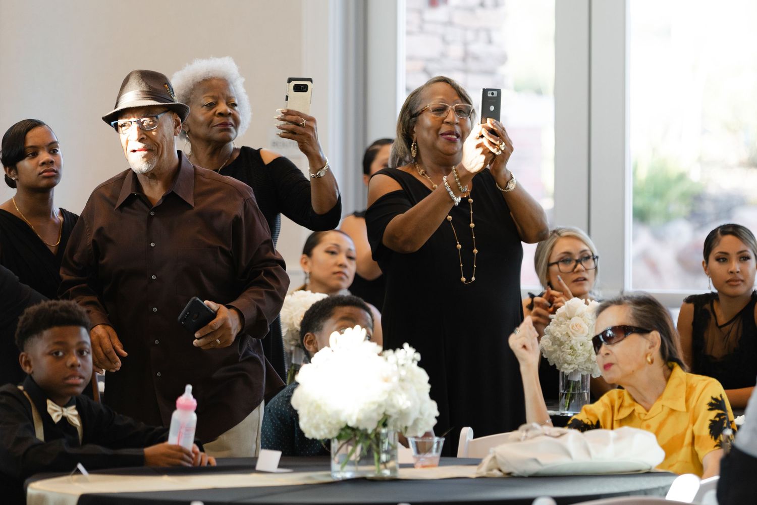 A group of people in formal attire react with joy and laughter during what appears to be a celebration event.
