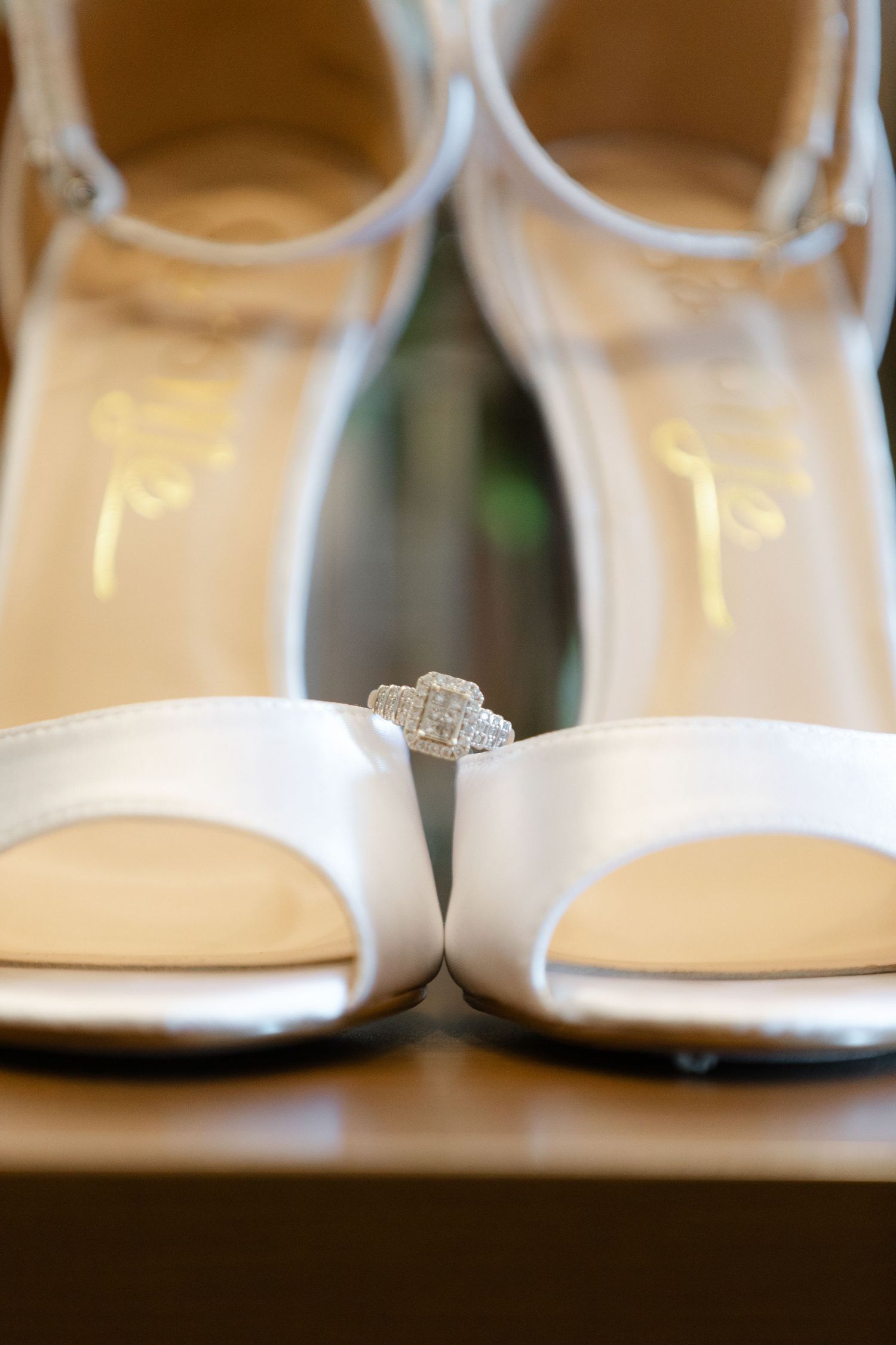 Close-up view of elegant white patent leather bridal shoes arranged in a row with shallow depth of field.