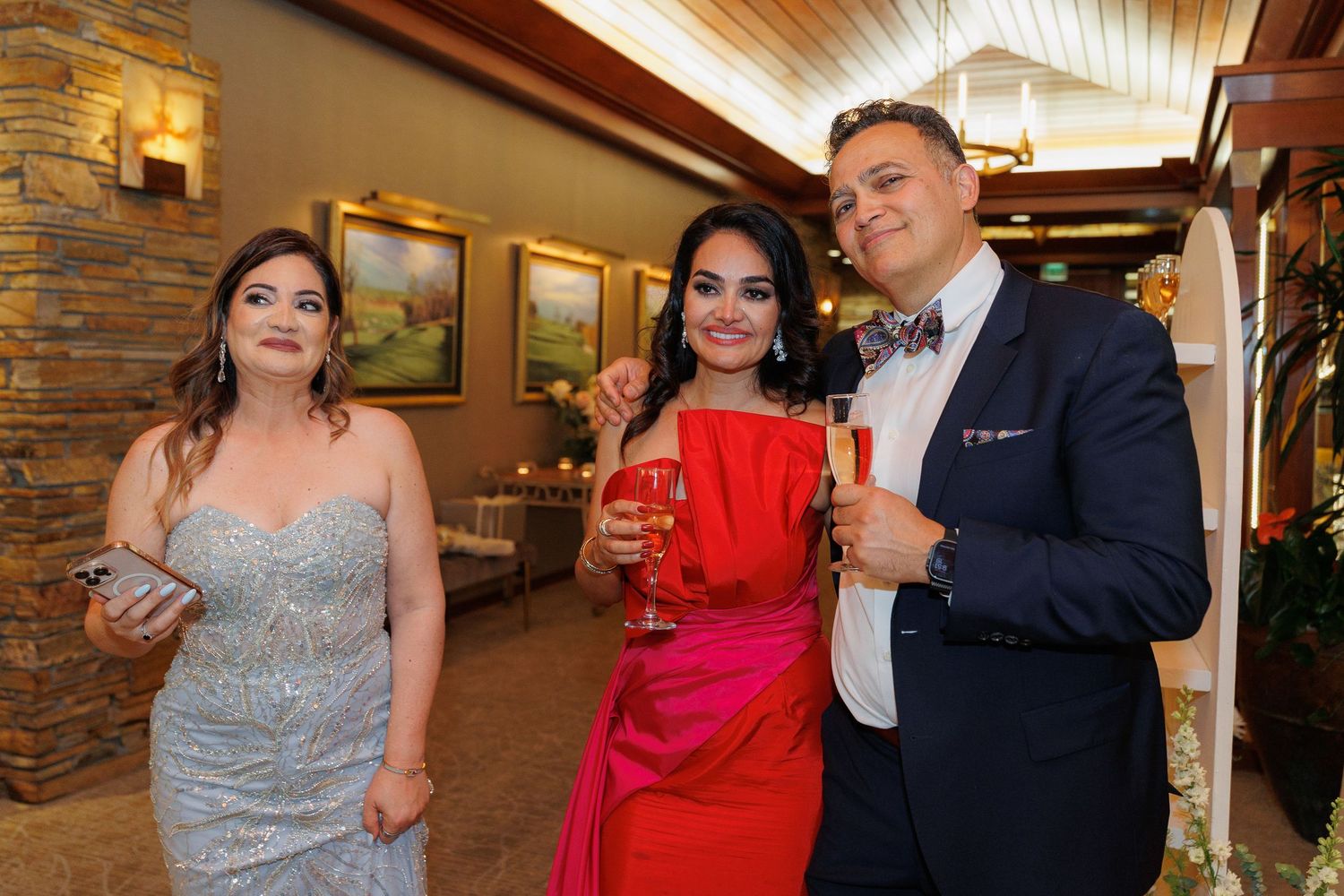 Guests in formal attire dancing and celebrating at an elegant indoor venue with stone walls and wood ceiling.