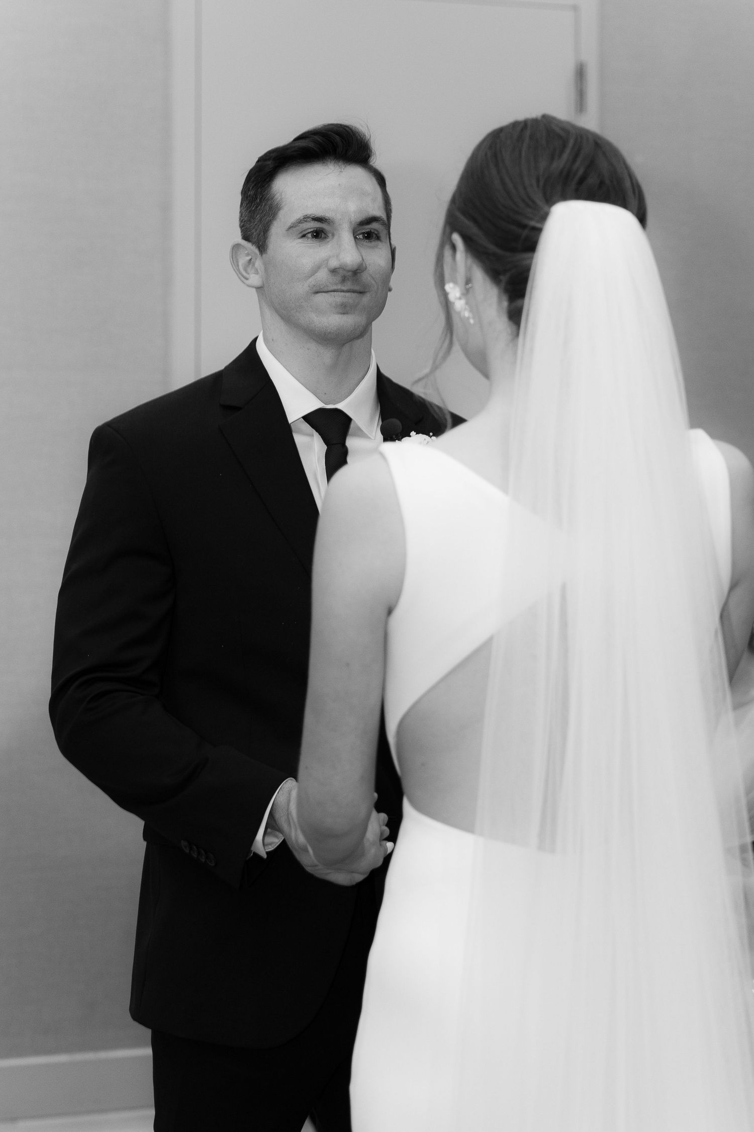 Black and white wedding photo series showing intimate moments between bride in white veil and groom in dark suit.