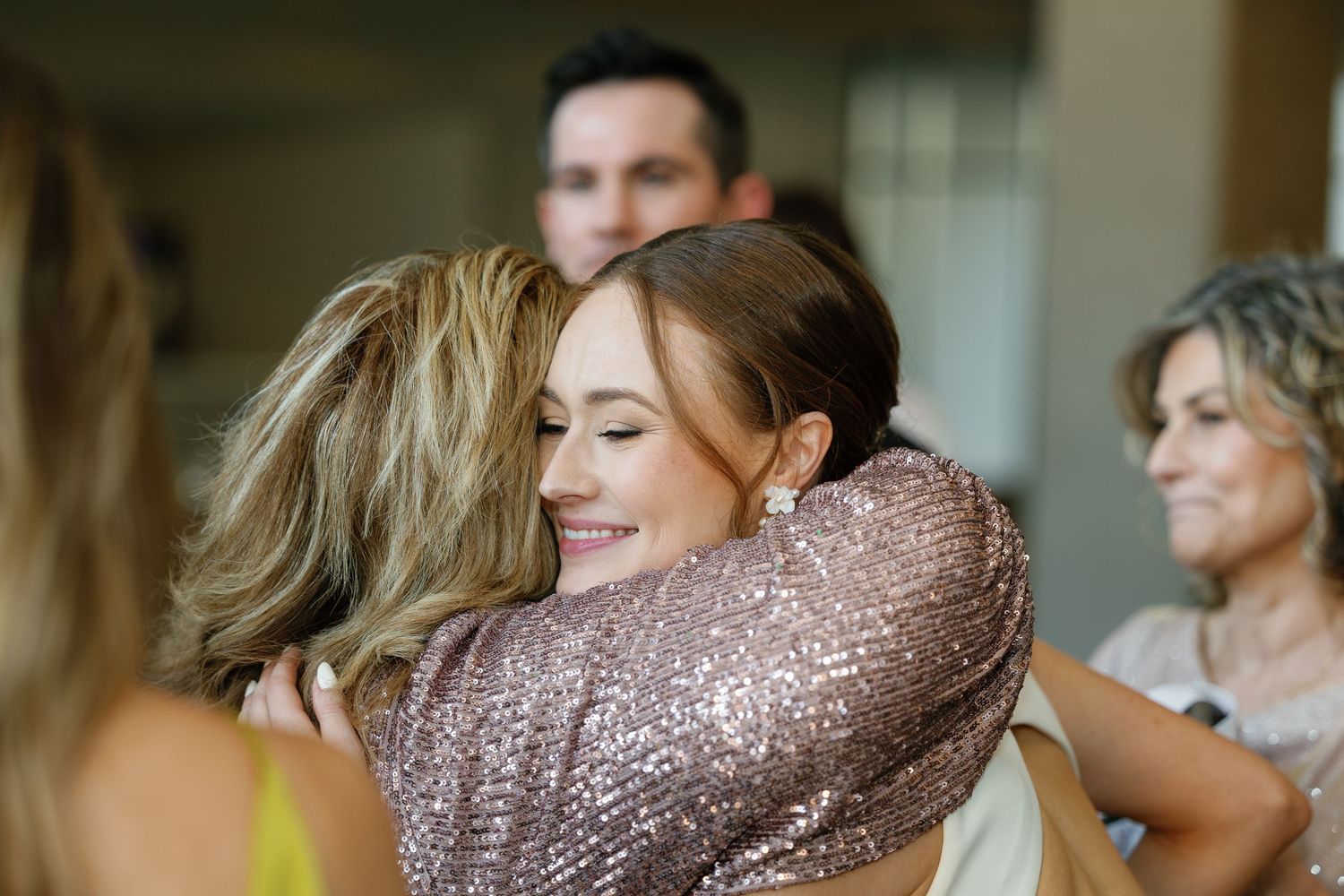 A wedding party celebrates together with laughter and joy in a light-filled venue.