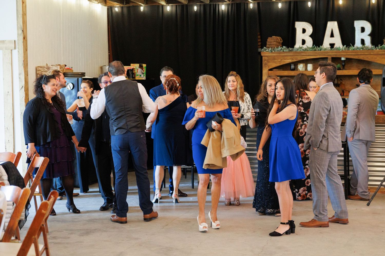 Guests in formal attire mingle and socialize at a bar area during an elegant event.