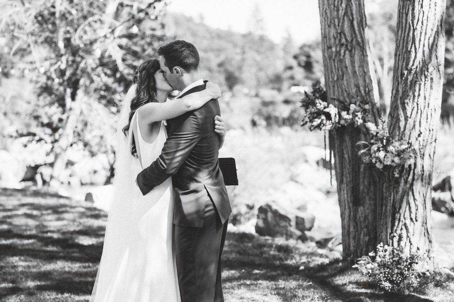 Black and white photo collage showing romantic moments of a couple embracing outdoors in a natural setting.