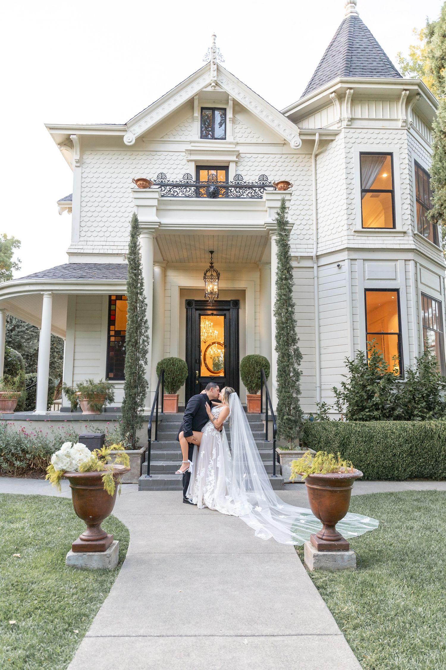 Victorian-style white house exterior with romantic wedding photo moments on the steps.
