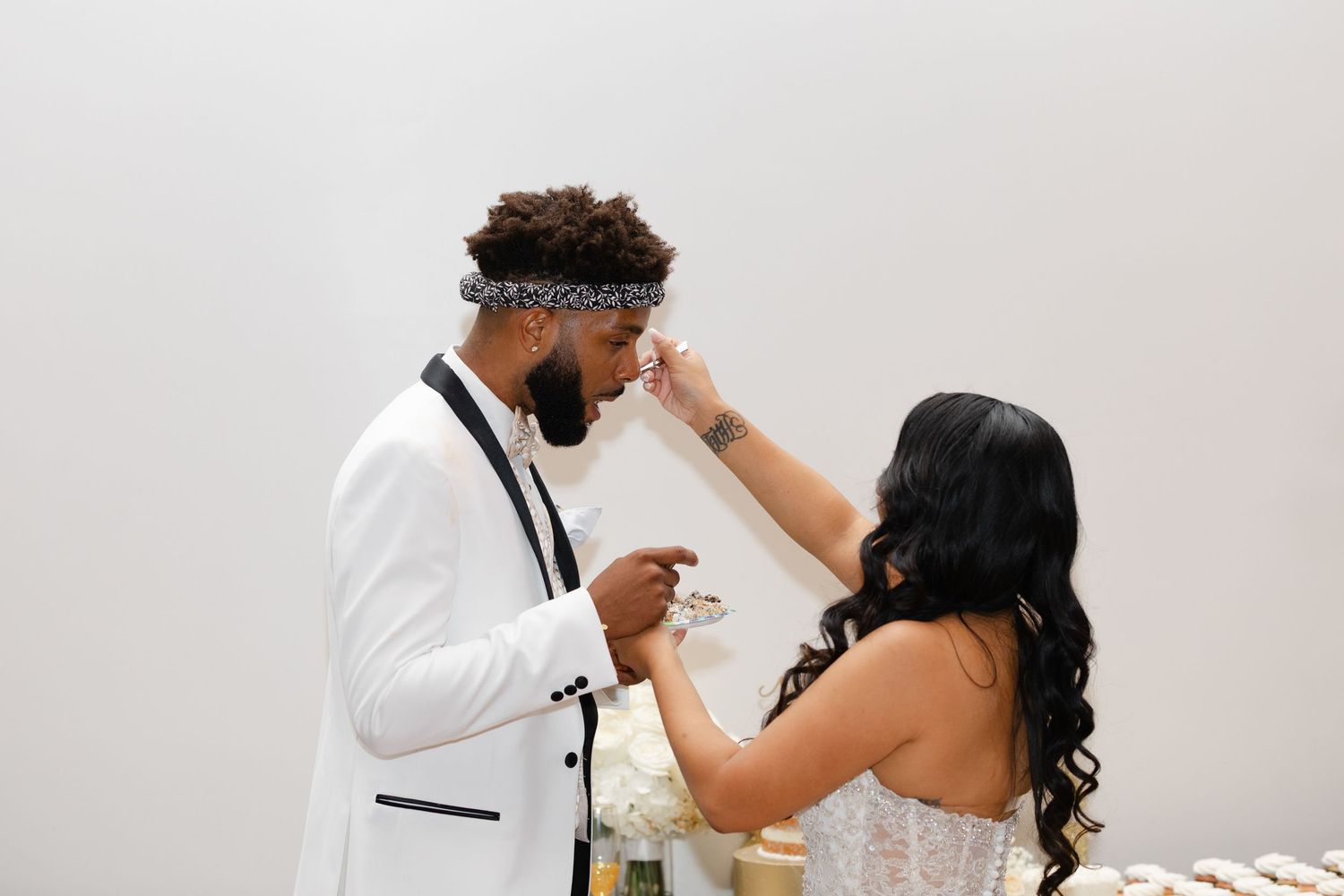 A couple shares an intimate moment during their wedding ceremony in a white room.