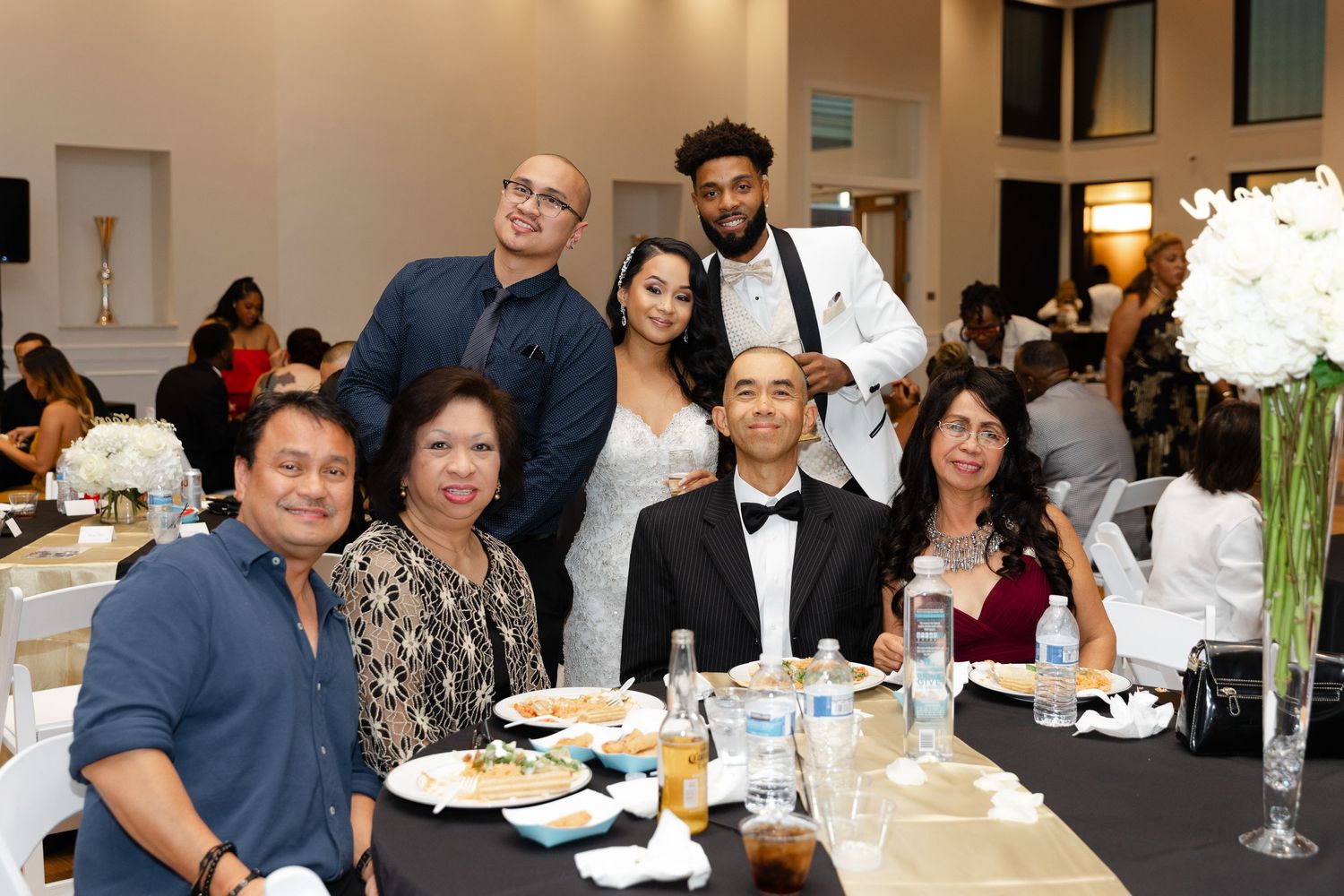A group of people enjoying a formal dinner event at an elegant banquet table with white tablecloths and place settings.