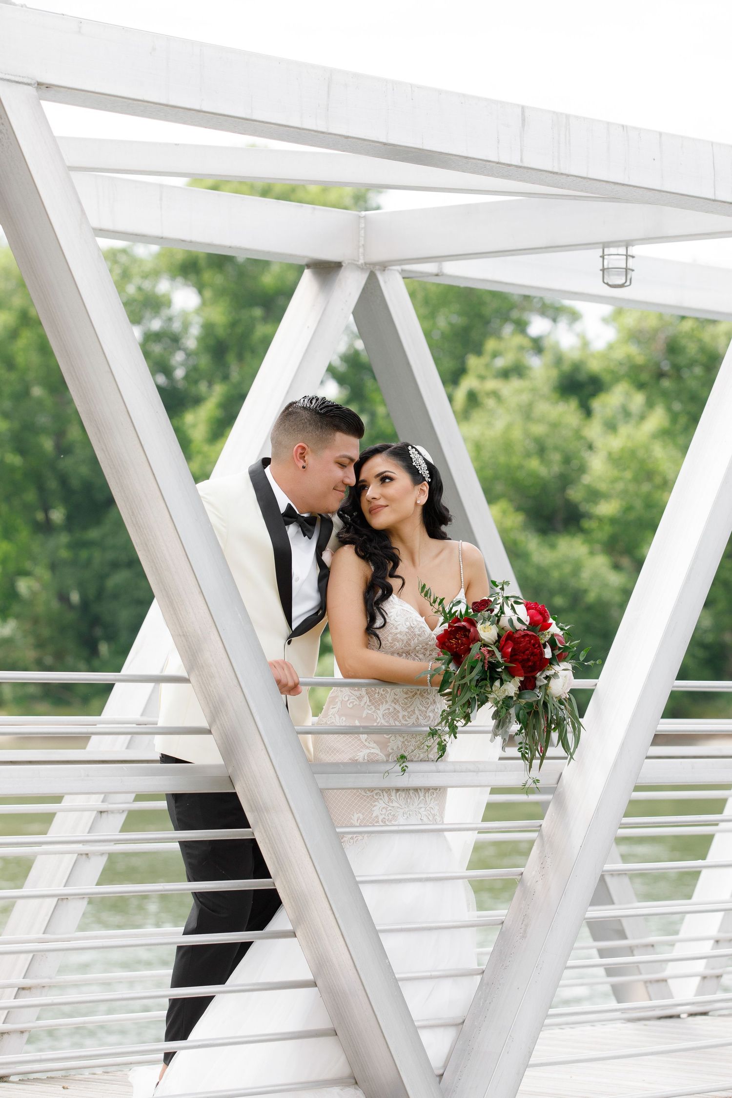 A romantic wedding couple shares intimate moments on a modern white architectural bridge with geometric railings.